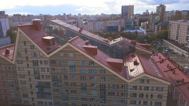 Top down aerial view of a beautiful residential building with red tiled roof. Art. Modern house in the city with a green park behind it, architecture concept.