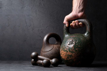 Man holds old heavy sports weight 32 kg on dark background
