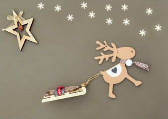 christmas flat lay with natural decoration  wooden Christmas tree toys Deer pulling sleigh,  and white snowflakes