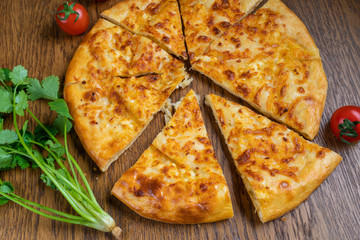 Adjarian Khachapuri with Adyghe cheese and egg yolks and slices of butter is on a wooden board sprinkled with flour.