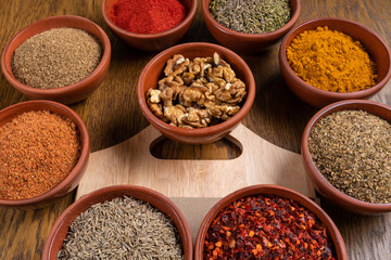 A selection of various colorful spices on a wooden table in bowls