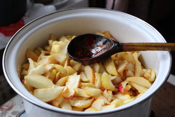  photo apples.they're in a big pot.fruits are cut into slices, pieces.cooking Apple jam.wooden spoon in a bowl.preparation of dessert in the home kitchen.