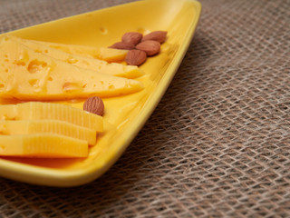  piece of cheese  and almonds with honey on a plate. burlap background. Rustic still life. 