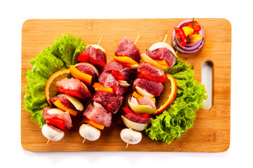 Uncooked shashlik on cutting board on white background