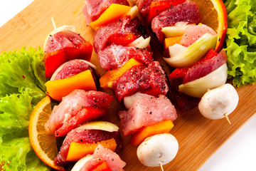 Uncooked shashlik on cutting board on white background