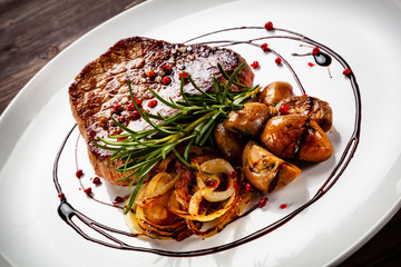 Grilled sirloin steak and vegetables on wooden background