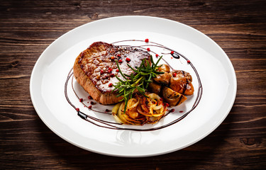 Grilled sirloin steak and vegetables on wooden background