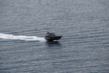 Light boat goes very quickly through the water to the sea on a summer sunny day