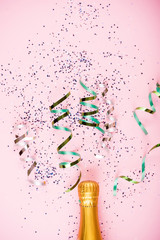 Flat lay of Celebration. Champagne bottle with colorful party streamers on mint background.