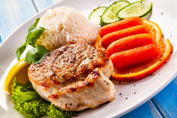 Roast steak with white rice and vegetables on wooden background
