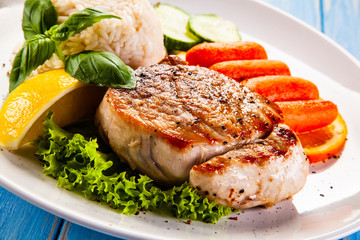 Roast steak with white rice and vegetables on wooden background