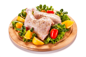Raw chicken thighs and vegetables on white background 