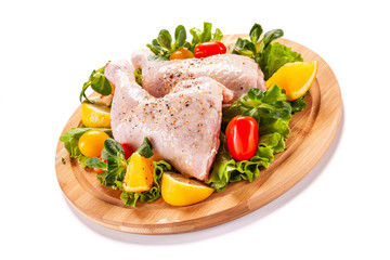 Raw chicken thighs and vegetables on white background