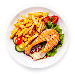 Barbecued salmon, french fries and vegetables on white background