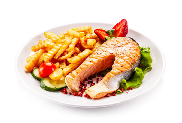 Barbecued salmon, french fries and vegetables on white background