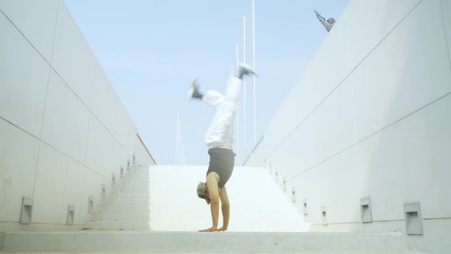 Young man doing hip hop dance on the stair with West Irian Liberation statue background. Shot in 4k resolution