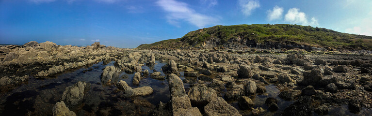 Fototapeta na wymiar The coast of France. The stone bottom of the bay. Low tide. Sharp stones. Le Gris Nez. 