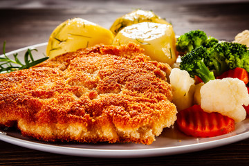 Schnitzel with boiled potatoes on timber background