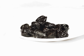 dried plums on a white plate with white background