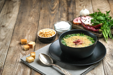 Pea soup with bacon, herbs and bread crumbs on a rustic background copy space.