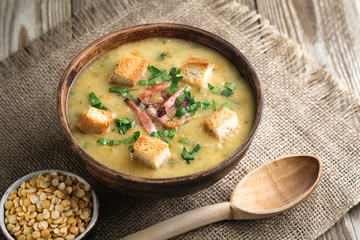 Pea soup with bacon, herbs and bread crumbs on a rustic background copy space.