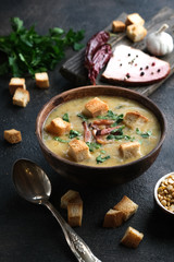 Pea soup with bacon, herbs and bread crumbs on a dark background copy space.