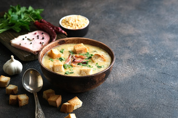 Pea soup with bacon, herbs and bread crumbs on a dark background copy space.