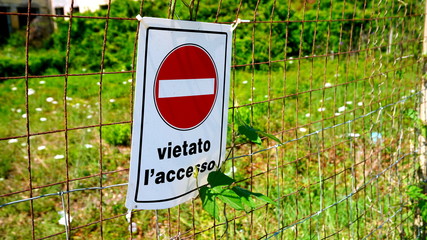 sign prohibited in Italian written on a wire mesh in the sun, with a blurred background