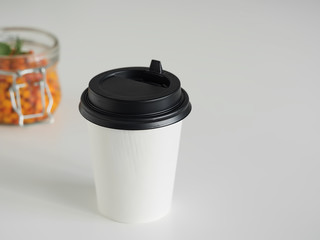 Sea buckthorn tea with lemon, honey, ginger and mint in a paper cup. Close-up. Healthy herbal tea. Near the jar with sea buckthorn berries.