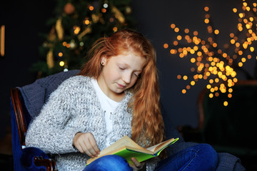 Teen girl is reading a book on Christmas Eve. The concept of holidays, merry christmas and...