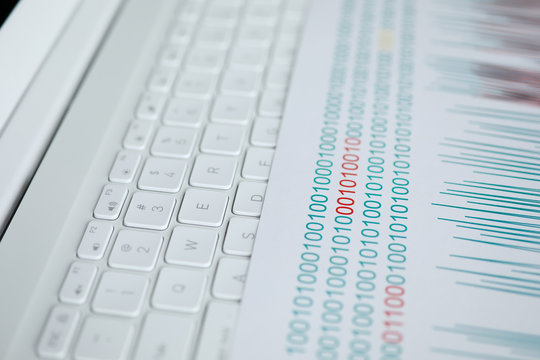 Numeric codes lie on paper on white laptop.