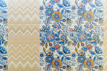 Square ceramic tiles in the form of blue-yellow leafy and floral patterns on the wall in the bathroom. Floral patterns alternate with beige scalloped lines