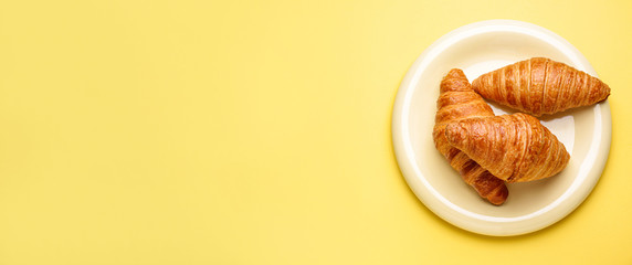 Plate with sweet croissants on color background with space for text