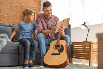 Father and his little son with guitar at home
