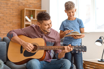Obraz premium Father and his little son with guitar at home