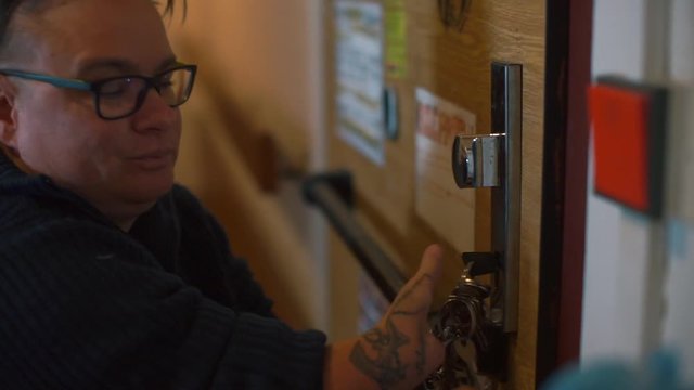 A woman with missing hands opens the door lock of the house.