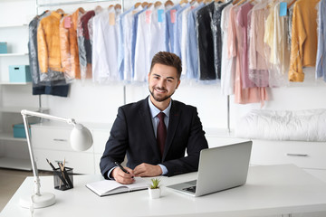 Young male worker sitting at workplace at dry-cleaner's