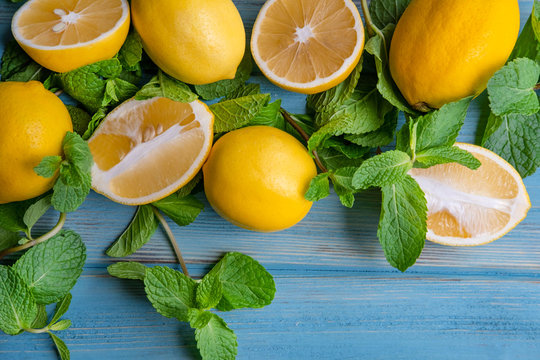 Sliced fresh lemons with mint on a blue wooden background with place for copy space. Background with citrus fruits. Vitamin C. Fresh lemon background. Flat lay, top view.