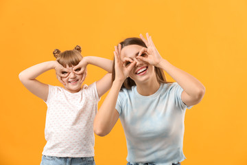 Portrait of happy mother and daughter having fun on color background
