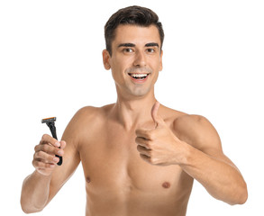 Fototapeta premium Handsome young man with razor showing thumb-up on white background