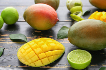 Sweet ripe mangoes and limes on dark wooden background