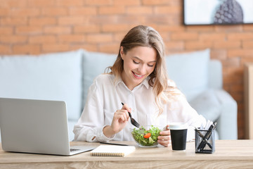 Woman eating healthy vegetable salad in office