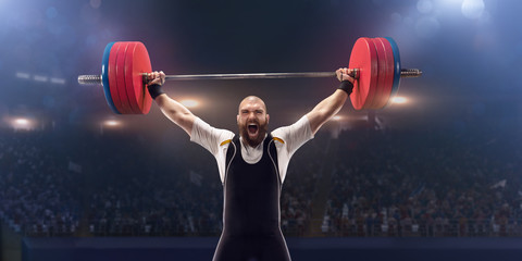 Male athlete is lifting a barbell on a professional stadium. Stadium and crowd are made in 3d. - obrazy, fototapety, plakaty