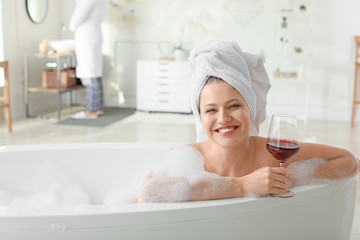 Beautiful young woman drinking wine while taking bath