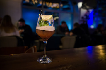 Glass of red cocktail with lime and mint on bar counter