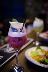 Glass of purple cocktail on the table in restaurant