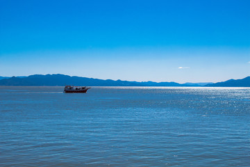 Tropical blue sea in sunny day and boat in the blue mountains  in Florian&oacute;polis