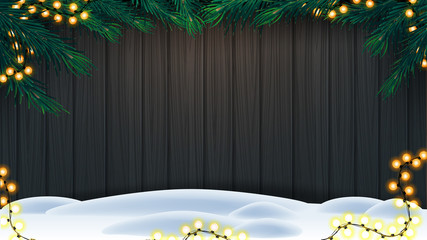 Christmas background, wooden fence of boards with frame of Christmas tree branches, garland of yellow bulb lights and snow on floor