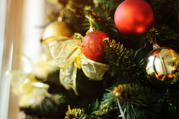 Decorated Christmas tree with golden and red toys closeup. 
