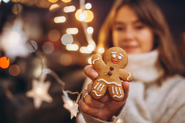concept for cafe or bakery for Christmas holidays: smiling woman holding gingerbread cookies and showing it to camera, selective focus, noise effect